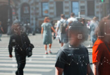 Crowd of people crossing a street with digital overlays indicating facial recognition technology