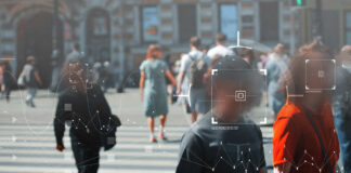 Crowd of people crossing a street with digital overlays indicating facial recognition technology