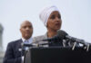 Ilhan Omar speaking at a press conference with André Carson in the background