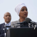 Ilhan Omar speaking at a press conference with André Carson in the background