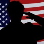 Silhouette of a person saluting in front of an American flag