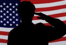 Silhouette of a person saluting in front of an American flag