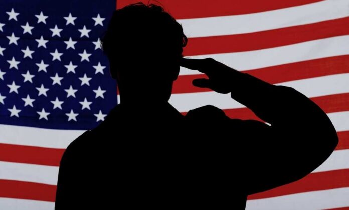 Silhouette of a person saluting in front of an American flag