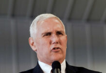 A man in a suit speaking passionately into a microphone