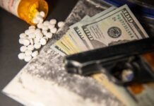 A handgun, cash, and prescription pills scattered on a surface