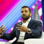 A speaker gesturing while discussing on stage at a conference