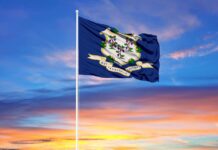 Connecticut state flag waving against a colorful sunset