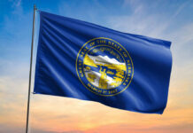 Nebraska state flag featuring the state seal against a sunset sky