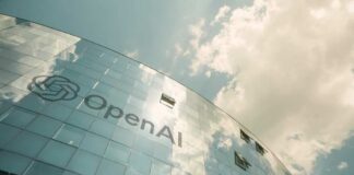 A modern glass building with the OpenAI logo against a cloudy sky