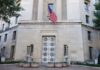 Facade of a government building featuring the American flag and decorative entrance