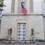 Facade of a government building featuring the American flag and decorative entrance