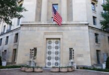 Facade of a government building featuring the American flag and decorative entrance
