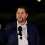 A man in a suit delivering a speech at night with a microphone