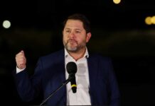 A man in a suit delivering a speech at night with a microphone