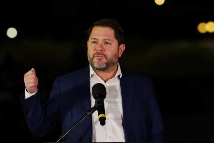 shutterstock_2745051661.jpg A man in a suit delivering a speech at night with a microphone