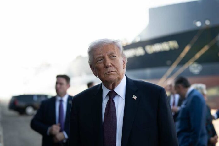 shutterstock_2747572781.jpg A political figure in a suit looking thoughtfully at an outdoor event with a ship in the background