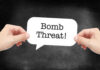 Hands holding a speech bubble with the text 'Bomb Threat'