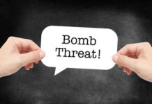 Hands holding a speech bubble with the text 'Bomb Threat'