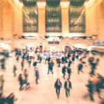 A busy train station filled with blurred figures of people moving