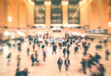 A busy train station filled with blurred figures of people moving
