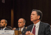 A man in a suit sitting at a table during a congressional hearing