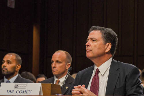 A man in a suit sitting at a table during a congressional hearing
