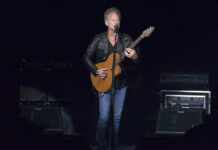 Musician performing on stage with an acoustic guitar