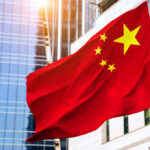 Chinese flag waving in front of modern buildings