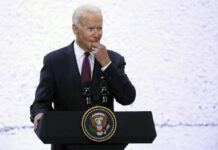 Stroke Scare Exposed: Was Biden’s Health Covered Up? A man in a suit speaking at a podium with a presidential seal