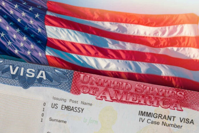 shutterstock2456694351jpg Close-up of a US visa with an American flag in the background