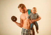 Internet EXPLODES Over Parenting Debate A muscular man lifting a dumbbell while holding a smiling baby