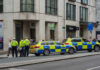 Police officers gathered near two marked police cars in an urban setting