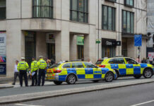 Police officers gathered near two marked police cars in an urban setting