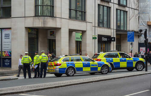 Police officers gathered near two marked police cars in an urban setting