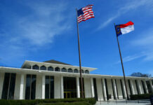 Government building with American and North Carolina flags under a clear blue sky