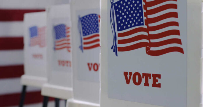 shutterstock_1743370412 Voting booths with American flags and VOTE signage