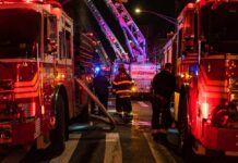 Firefighters and fire trucks at a nighttime emergency scene
