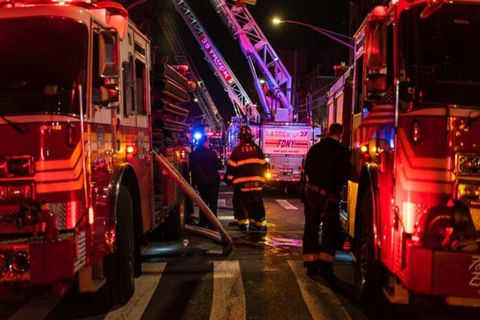 Firefighters and fire trucks at a nighttime emergency scene