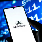 Shocking Turn: Judge Hits Disney in Carano Case! A smartphone displaying the Walt Disney logo with a blurred financial data background