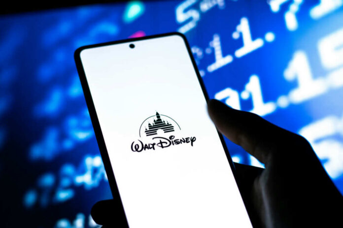 A smartphone displaying the Walt Disney logo with a blurred financial data background