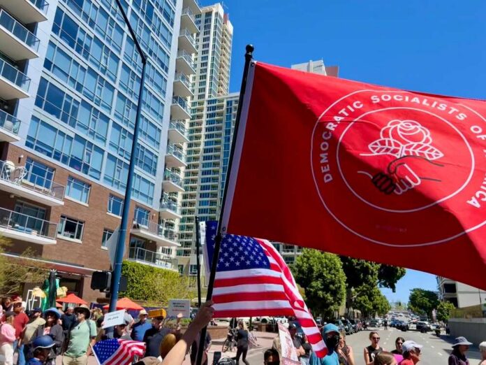San,Diego,,California,,United,States,-,June,5th,,2025:,San Protesters march in a city street holding a large red flag and U.S. flags