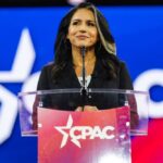 A woman speaking at a podium with a CPAC logo in front of a colorful background