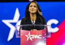 A woman speaking at a podium with a CPAC logo in front of a colorful background