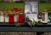 Memorial setup with candles, flowers, and a framed photograph