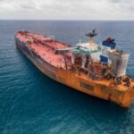 Iran’s ‘Green Fee’ Gambit — U.S. Fights Back! Aerial view of a large, rusty oil tanker in the ocean