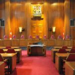 Interior view of a courtroom with wooden paneling and red seating