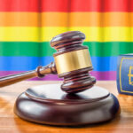 Shocking Block: Kansas Judge Freezes Gender Law A wooden gavel on a table with a rainbow flag in the background