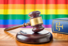 Shocking Block: Kansas Judge Freezes Gender Law A wooden gavel on a table with a rainbow flag in the background