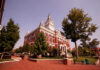 Historic red-brick courthouse with clock tower and trees in a sunny plaza