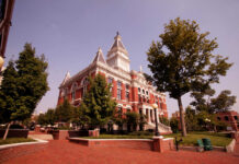 Historic red-brick courthouse with clock tower and trees in a sunny plaza